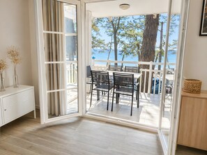 A room with a sliding glass door leading to an outdoor area with a table and chairs, a white cabinet, and a decorative item on a wooden cabinet.