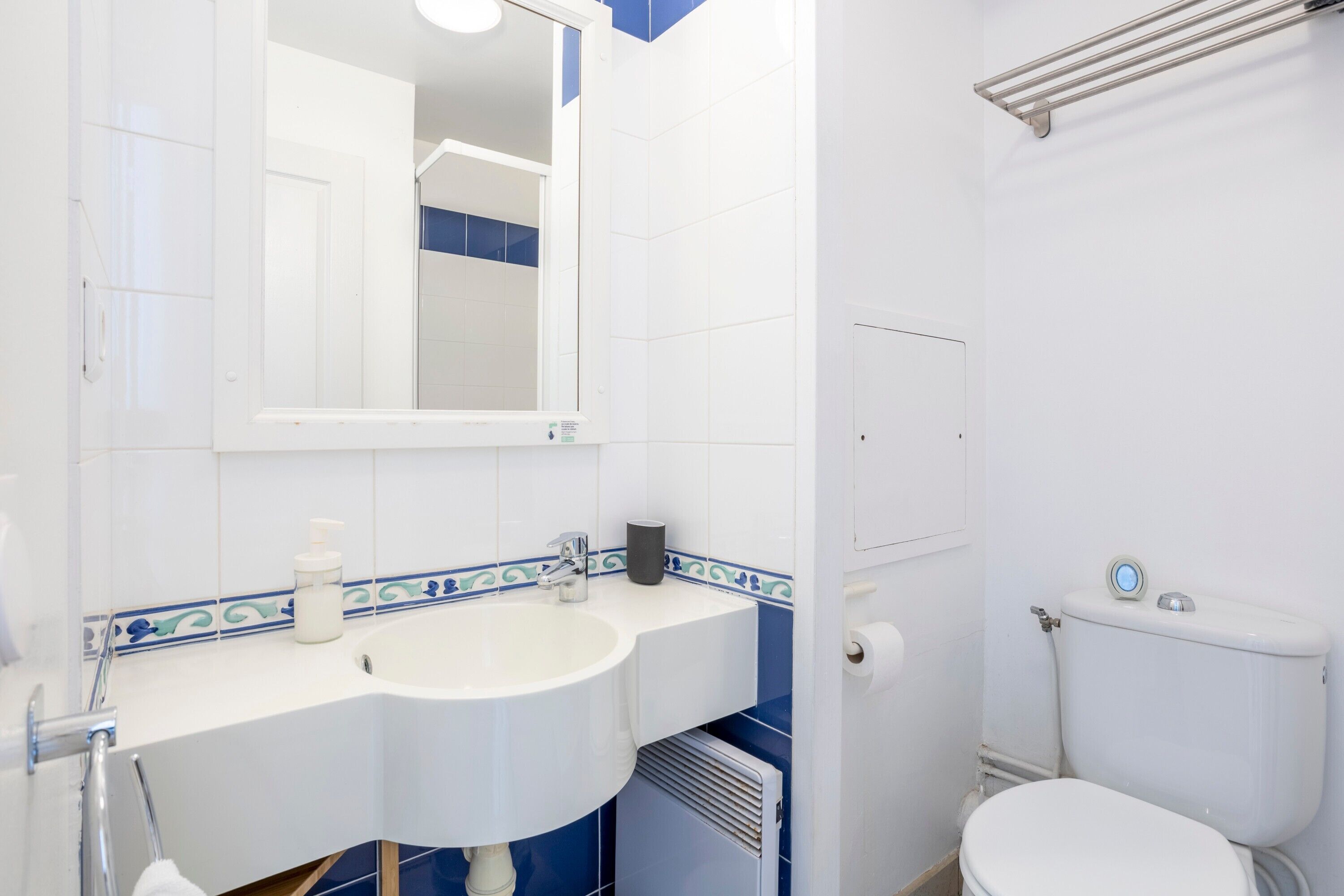 Een badkamer met een wit wastafel, spiegel en toilet.