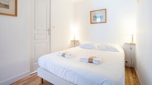 A neatly made bed with towels, a white door, and two bedside lamps. - L'Estuaire – River View, 20 Meters from Shops (Combrit)