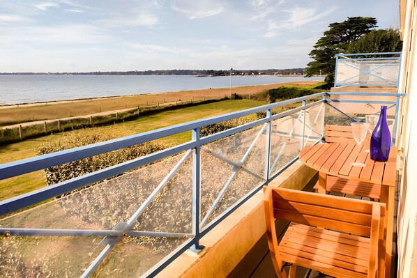 A balcony with a view of the beach and the sea.