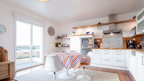Een moderne keuken met witte kastjes, een strepen tafelkleed en uitzicht door de schuifdeur.