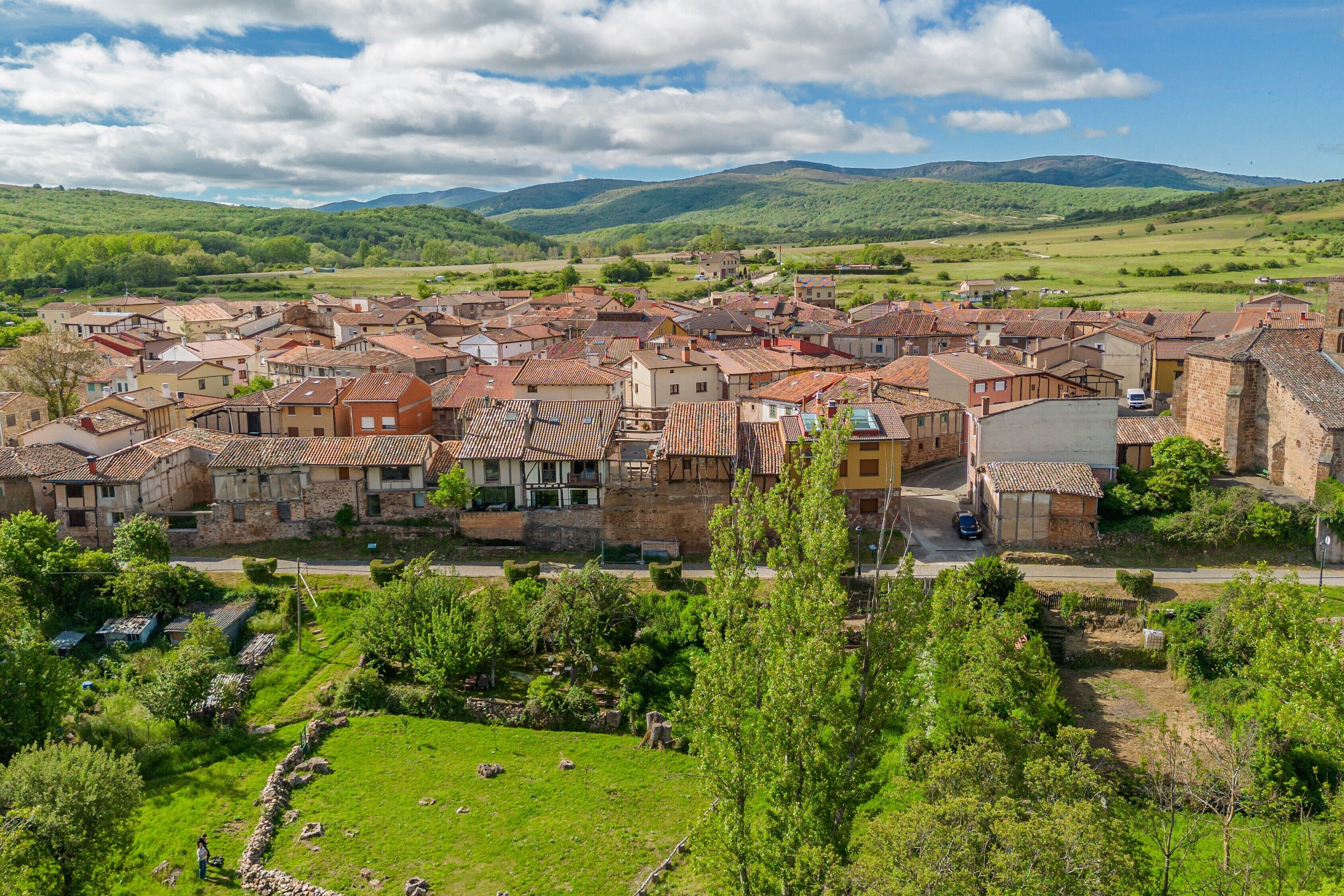 Un pueblo histórico con arquitectura tradicional, una plaza central y colinas verdes circundantes.