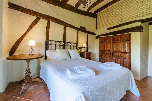 A bedroom with a bed, two bedside tables, a wooden wardrobe, and a chandelier.