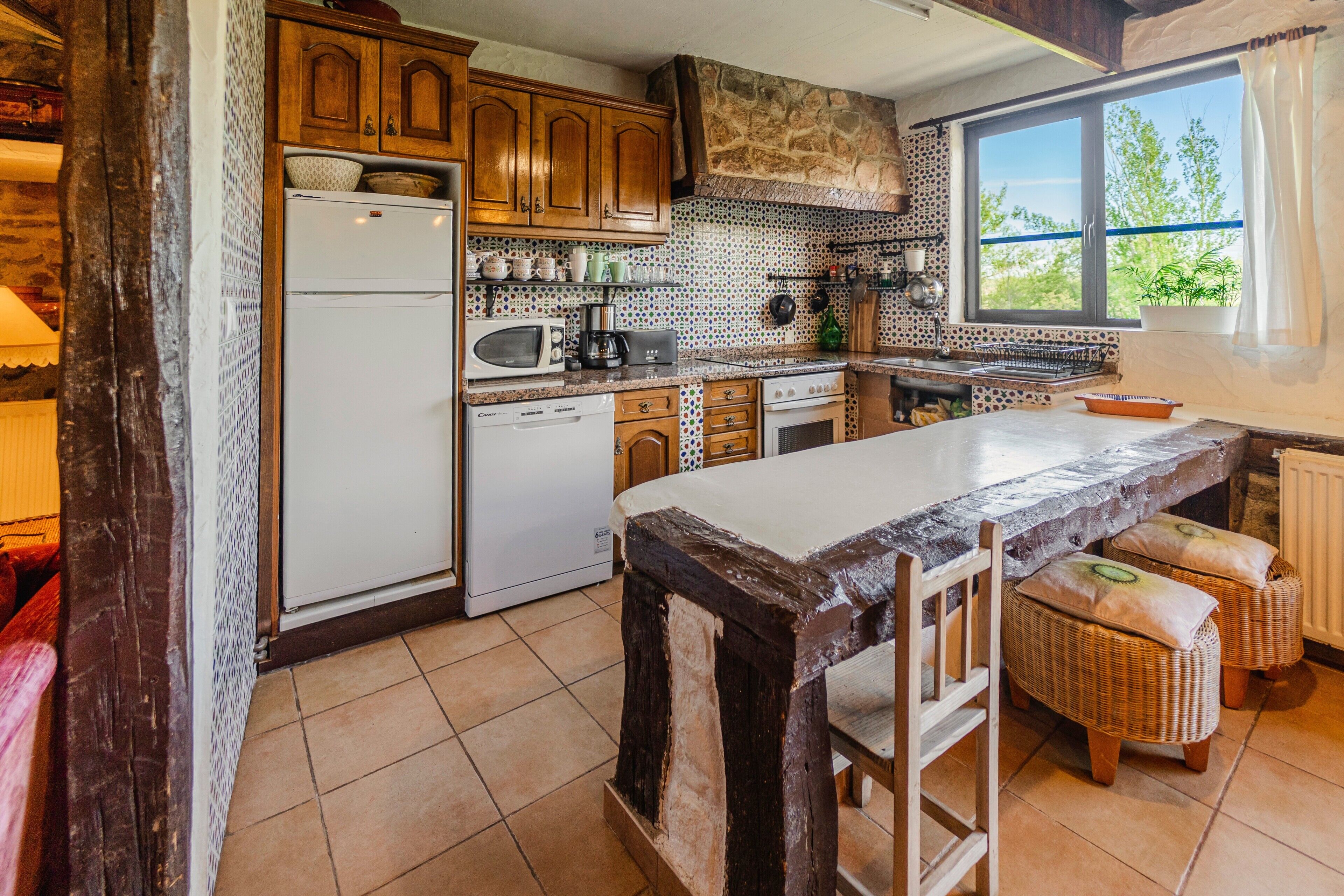 A kitchen with wooden cabinets, a large island, and a view through a window.