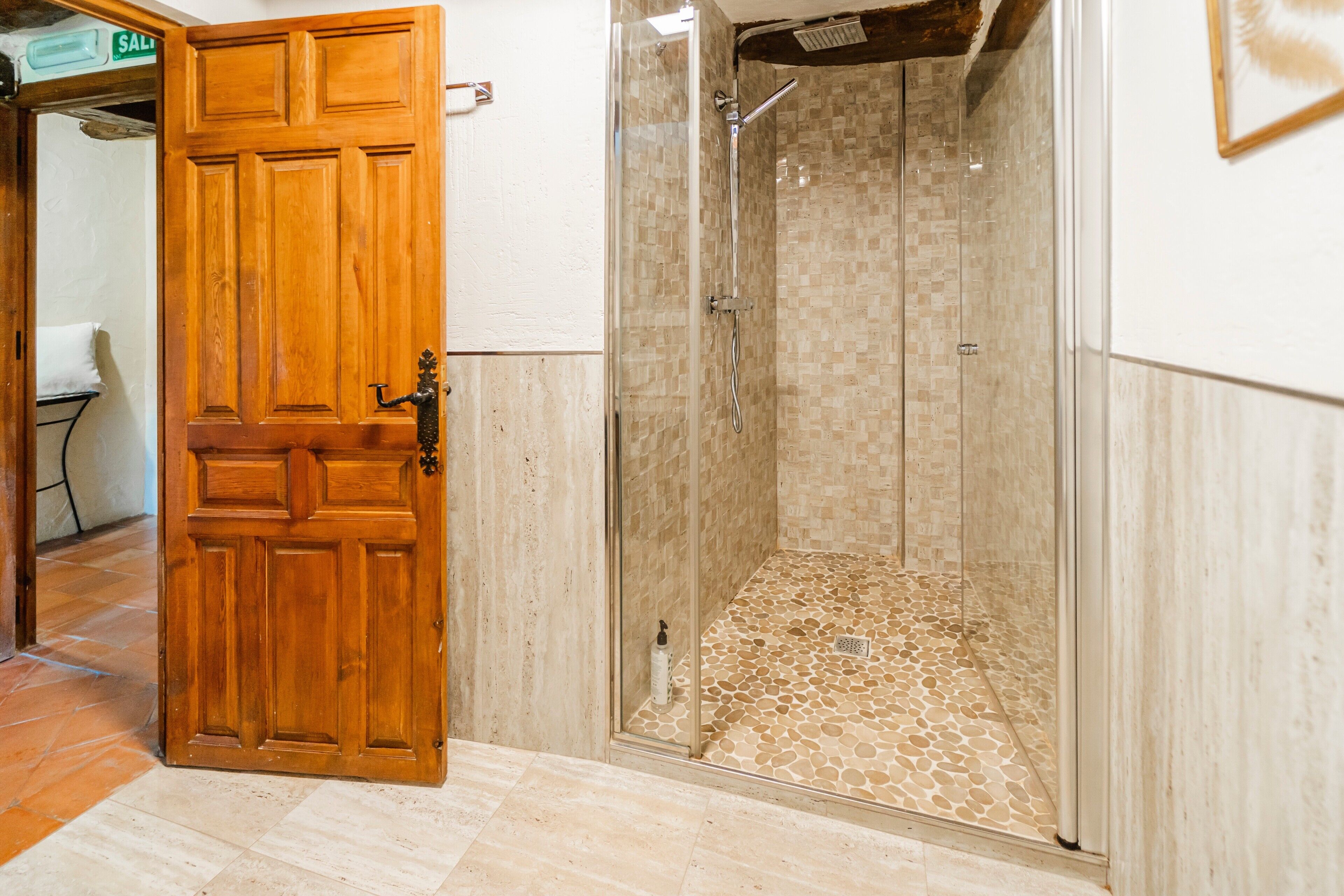 A wooden door leading to a shower area with a tiled floor.