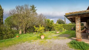 A garden with a gravel path, potted plants, and a stone structure. - Apartment 'Simone' with Shared Pool and Shared Garden (Massa Marittima)