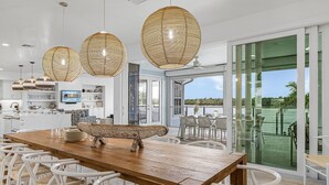 A modern kitchen with a large island, white cabinetry, and a view to the outdoors.