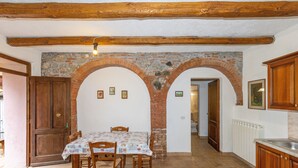 A dining area with a brick wall, wooden ceiling beams, and a tiled floor.
