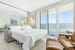 A hotel room with a bed, a seating area, and a balcony with a view of the sea. - Welcome to Oceans Twelve - Ocean View and Steps to the Beach - Roelens (Fort Myers Beach)