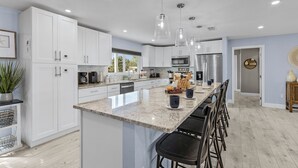 A modern kitchen with white cabinets, a granite countertop, and stainless steel appliances.