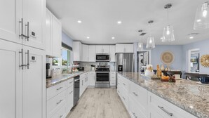 A modern kitchen with white cabinets, stainless steel appliances, and a granite countertop.