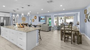 A modern kitchen with a large island, white cabinetry, and pendant lighting.