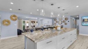 A spacious kitchen with a large island, pendant lights, and a dining area with a table and chairs.