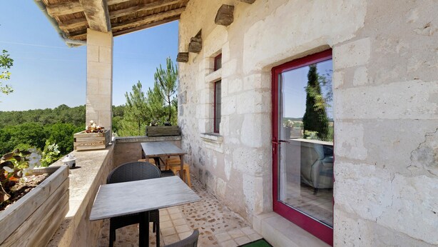 Une terrasse avec des meubles d’extérieur, un mur en pierre et une vue sur le paysage.