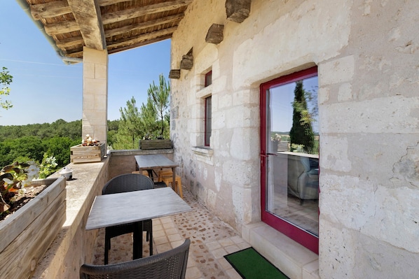A patio with outdoor furniture, a stone wall, and a view of the landscape.