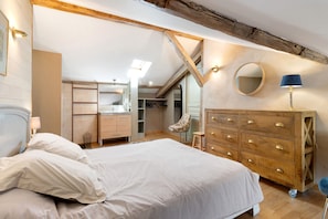 A bedroom with a bed, wooden dresser, and a chair.