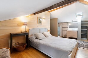 Een slaapkamer met een bed, nachtkastje, lamp en een houten vloer.