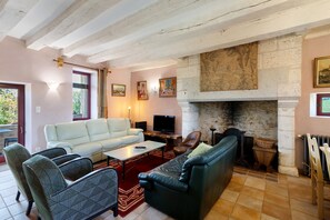 A living room with a fireplace, a sofa, a television, and a dining area.