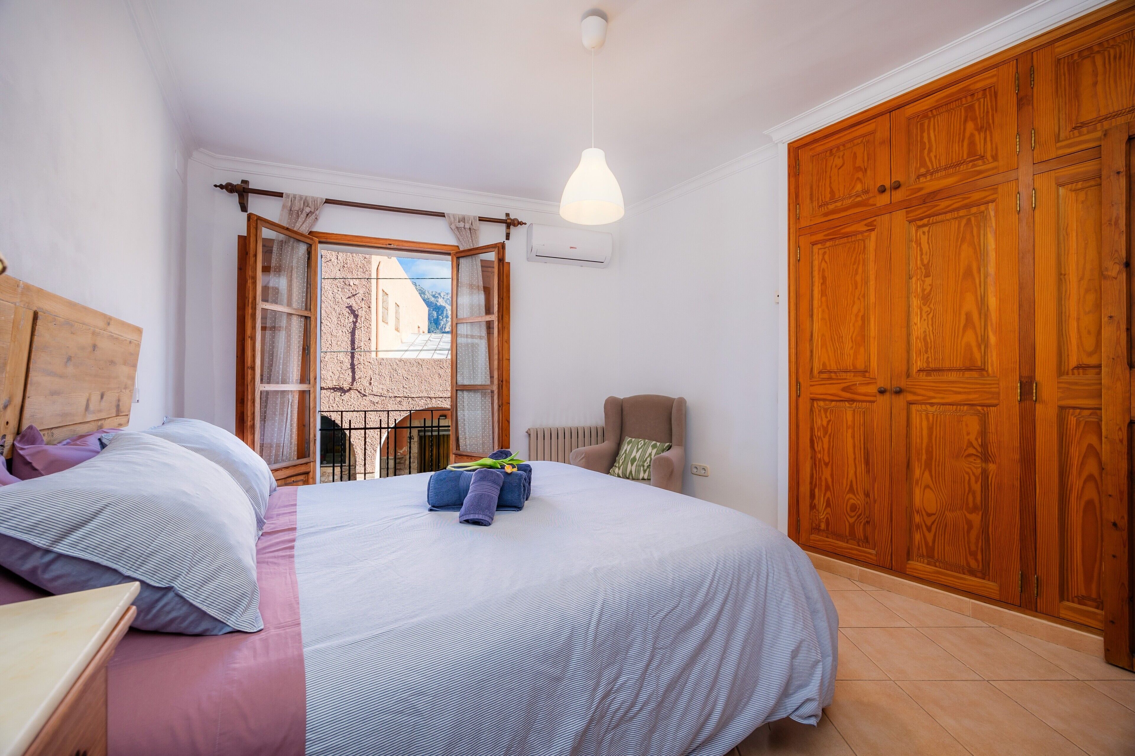 Une chambre à coucher avec un lit, une chaise, une armoire et une fenêtre avec des rideaux.