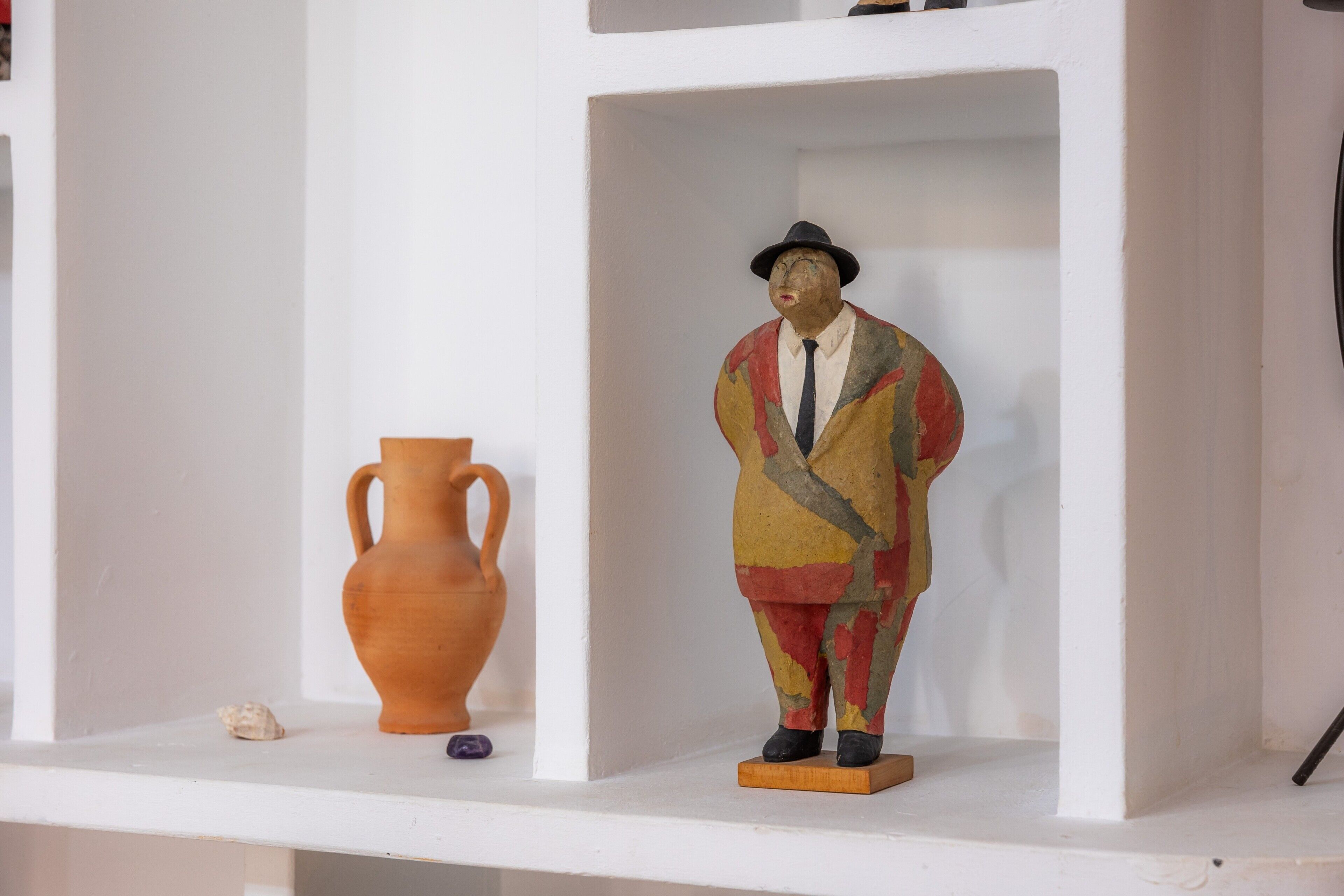 Une étagère avec un pichet en céramique, une figurine et un petit objet.
