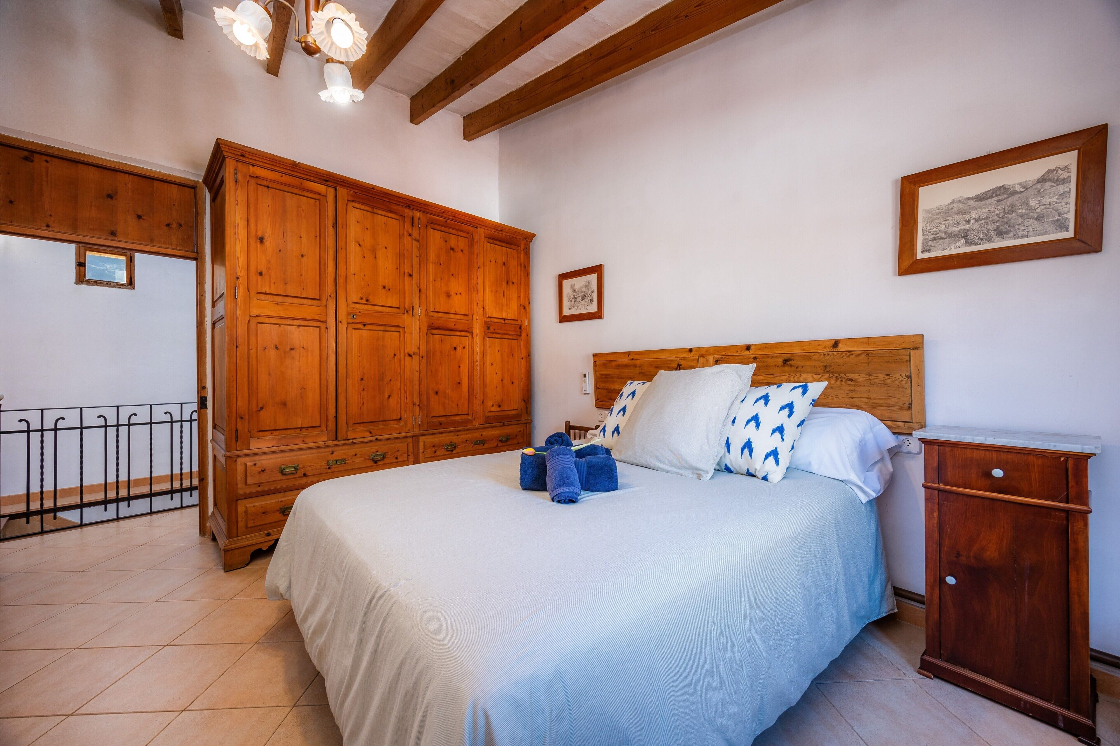 A bedroom with a wooden bed, a nightstand, a wardrobe, and a ceiling light fixture.