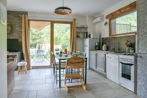 A kitchen with a dining table, chairs, a TV, and a view of the outdoors.