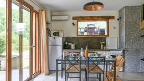 Une cuisine moderne avec une table à manger en verre, des chaises en bois et un pare-feu en pierre.