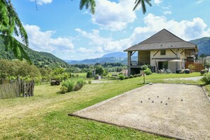 A house with a fenced yard, a gravel area, and a mountainous backdrop.