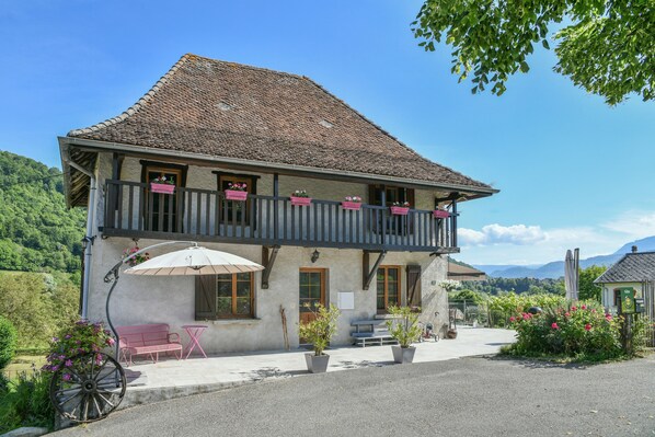 A two-story building with a balcony, outdoor seating, and potted plants. - Holiday Home 'La Maison Dauphinoise' with Mountain View, Wi-Fi and Air Conditioning (Saint Bueil)