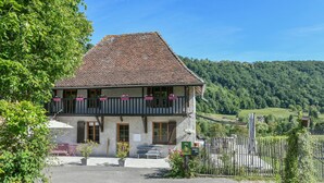 Un bâtiment à deux étages, doté d’un toit en pente, d’un balcon orné de plantes en pot et d’une allée gravillonnée.