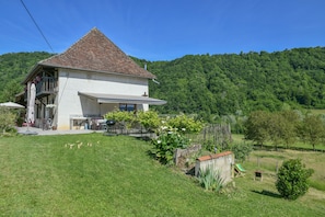 A house with a sloped roof, a balcony, and a garden with plants and a small shed.