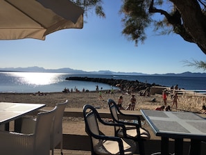 Un restaurant situé en bord de mer, avec une terrasse et une vue sur la mer et les montagnes.