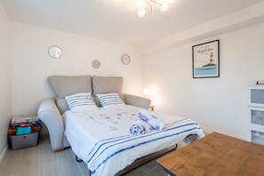 Un dormitorio con cama, mesitas de noche, una pequeña mesa de madera y un espejo colgado en la pared.