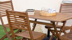 Une table en bois avec des chaises, un plateau avec des verres et des tasses à café, et un tableau encadré posé sur la table.