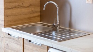 Une cuisine moderne dotée d’un évier en acier inoxydable, de meubles en bois et d’un plan de travail en marbre.