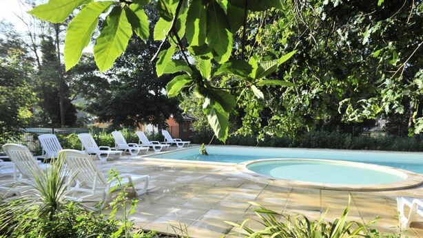 Uma área de piscina com espreguiçadeiras e vegetação.