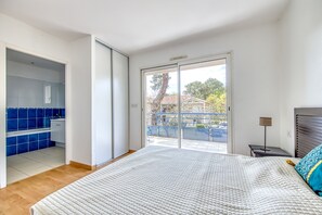 Una camera da letto con un letto, un bagno con piastrelle blu e un balcone con vista.