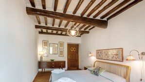 Ein Schlafzimmer mit Holzboden, einem Bett mit Steppdecke, einem Schminktisch, einer Tür und Wandlampen.