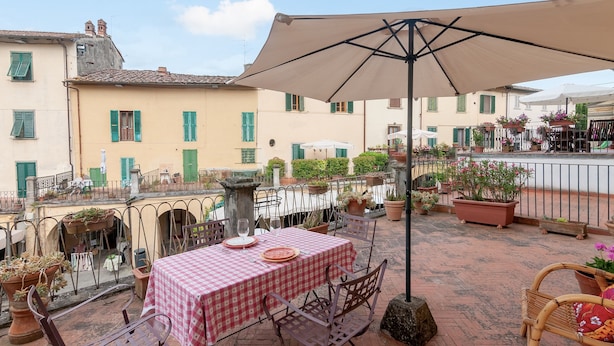 Eine Terrasse mit Esstisch, Gartenmöbeln und Topfpflanzen.