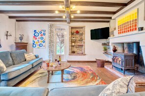 Un salon avec un canapé, une table basse, une cheminée, un téléviseur et un tapis aux couleurs vives.