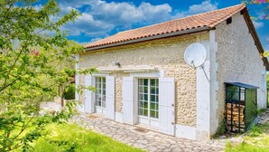 Un bâtiment en pierre avec un toit recouvert de tuiles, une antenne parabolique et un petit abri de jardin.