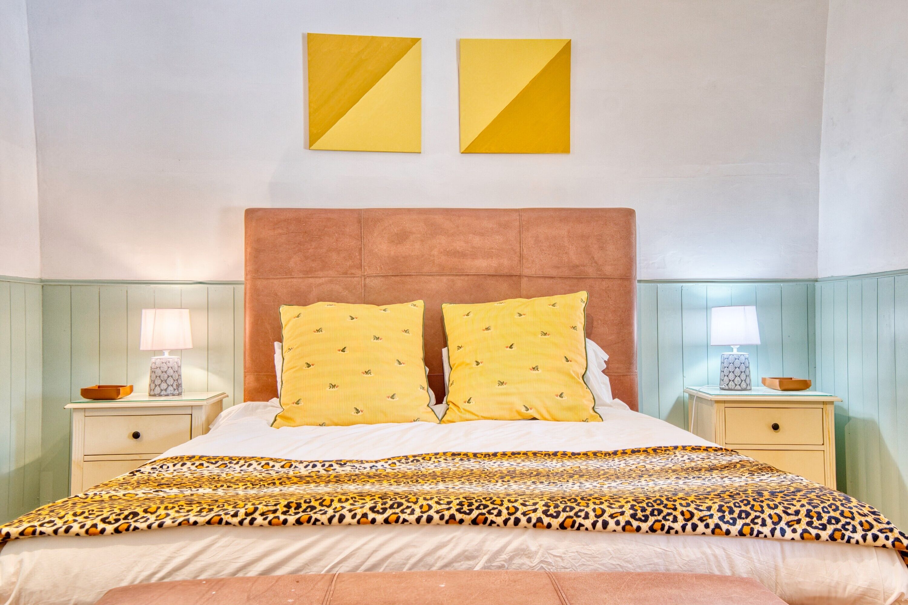 Un lit avec une couvre-lit à motifs, deux lampes de chevet et une tête de lit.