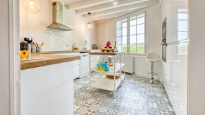 A kitchen with a tiled floor, a wooden countertop, a hanging light fixture, and a window with a view. - Charming Stone House with Pool and Enclosed Garden :
A Haven of Comfort and Serenity (Allemans)