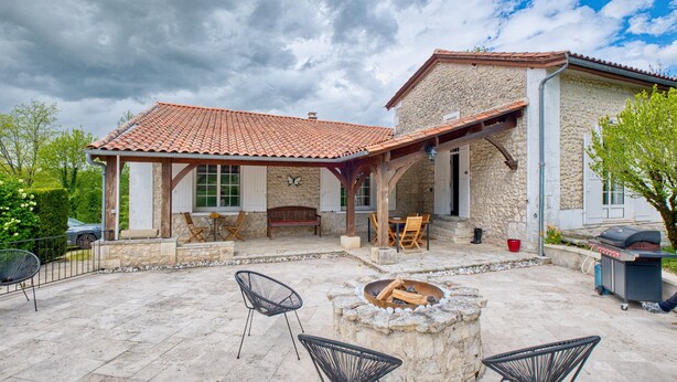 A stone building with a tiled roof, outdoor seating, a fire pit, and a barbecue grill. - Charming Stone House with Pool and Enclosed Garden :
A Haven of Comfort and Serenity (Allemans)