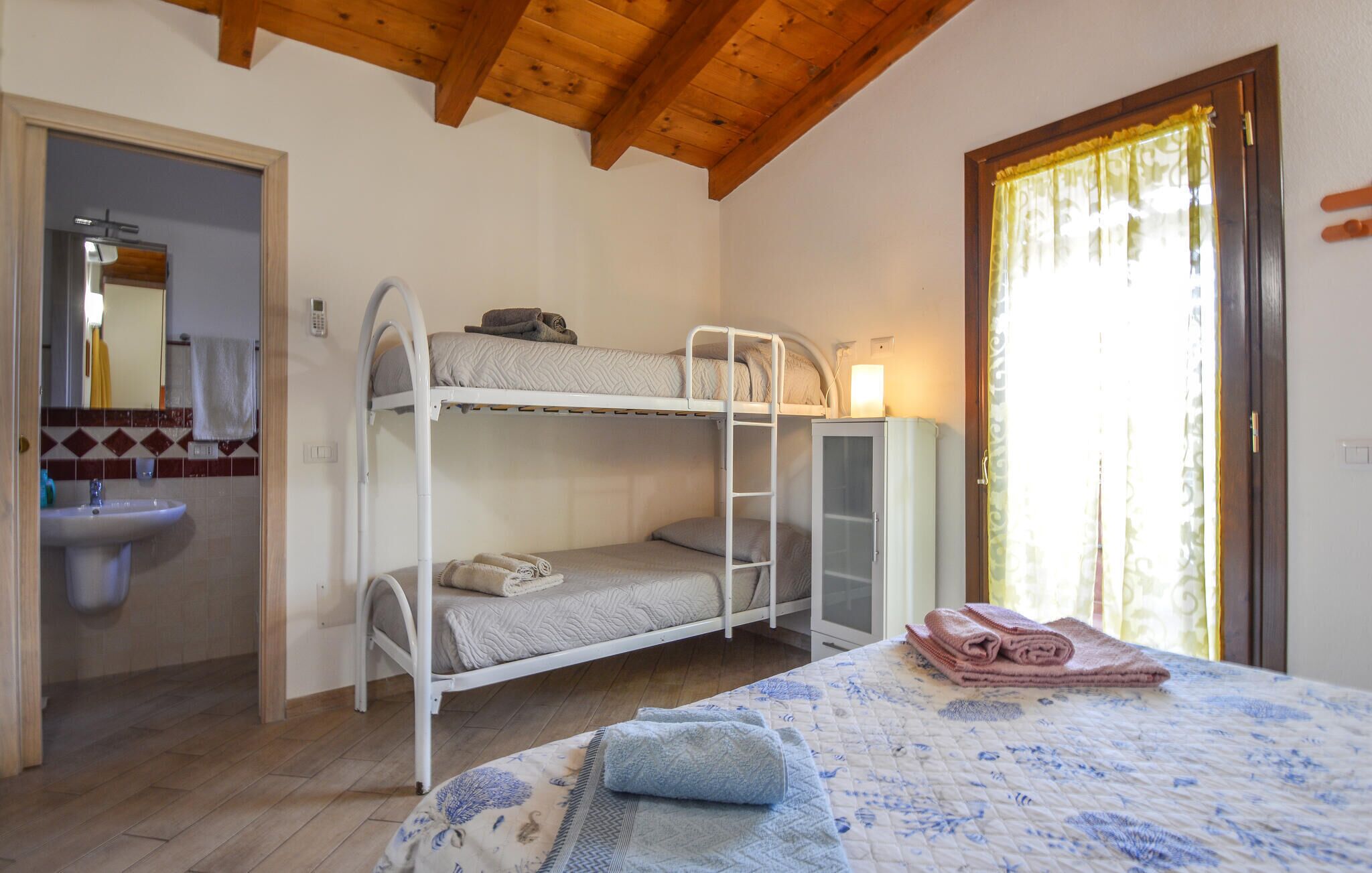 Dormitorio con literas, un lavabo, un armario y una puerta con cortina.