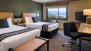 A hotel room with two beds, a desk, a chair, a TV, and a window with a mountain view. - Premier Double Room with Forest Views (Stevenson)