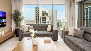 Un salon moderne avec un canapé gris, une table basse et un téléviseur fixé au mur.