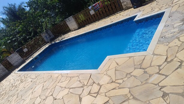 A swimming pool with a stone-tiled deck and a decorative fence. - Chácara Recanto Verde, a very cozy rural location  (Iperó)