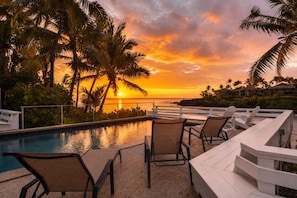 A poolside area with lounge chairs and a view of the sunset over the ocean. - Hale Moana | Your Luxury Kona Stay Starts Here! (Kailua Kona)