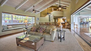 A spacious living room with a high ceiling, large windows, and a cozy seating area.